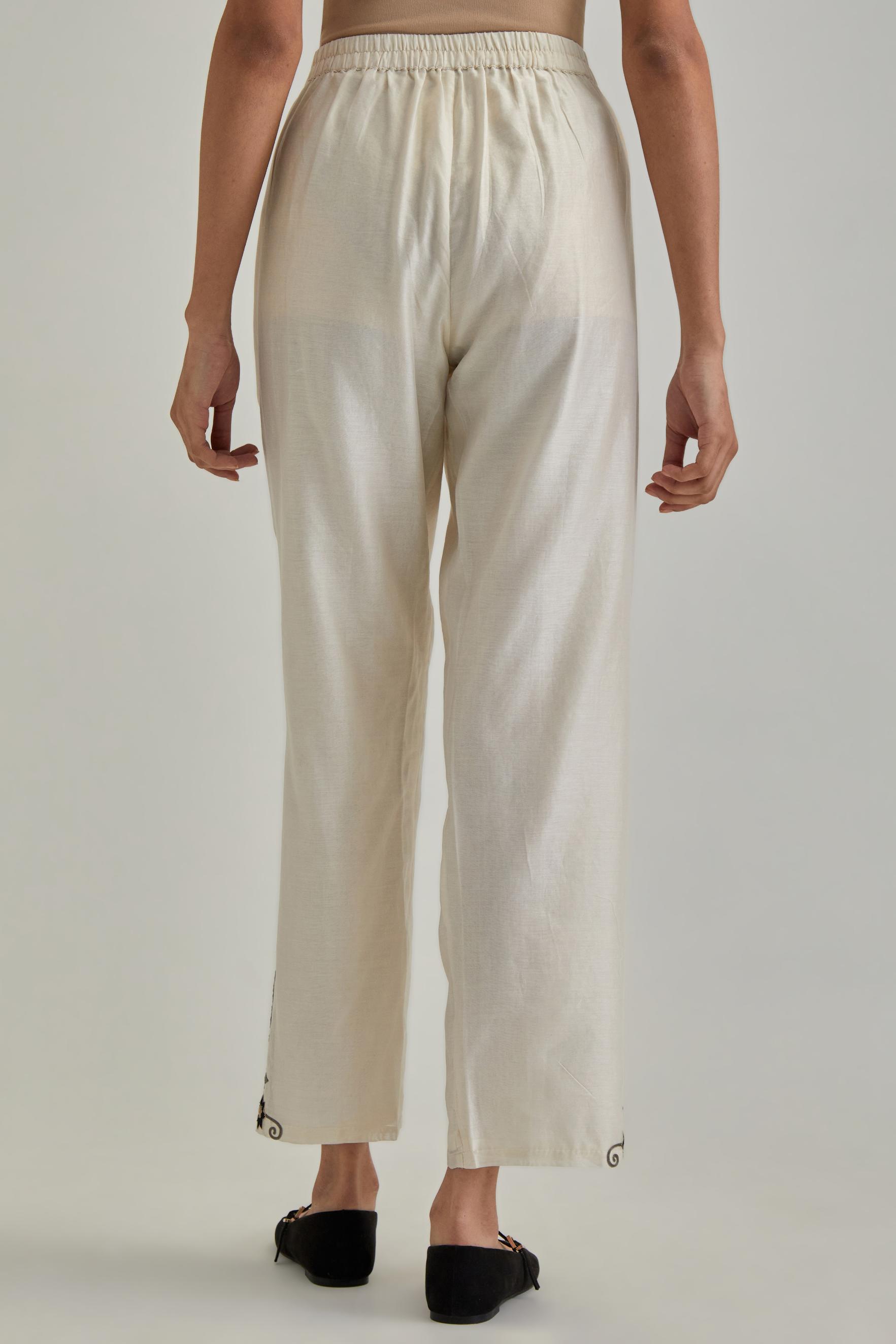 Off white silk Chanderi straight pants with earthy coloured appliqué at hem.