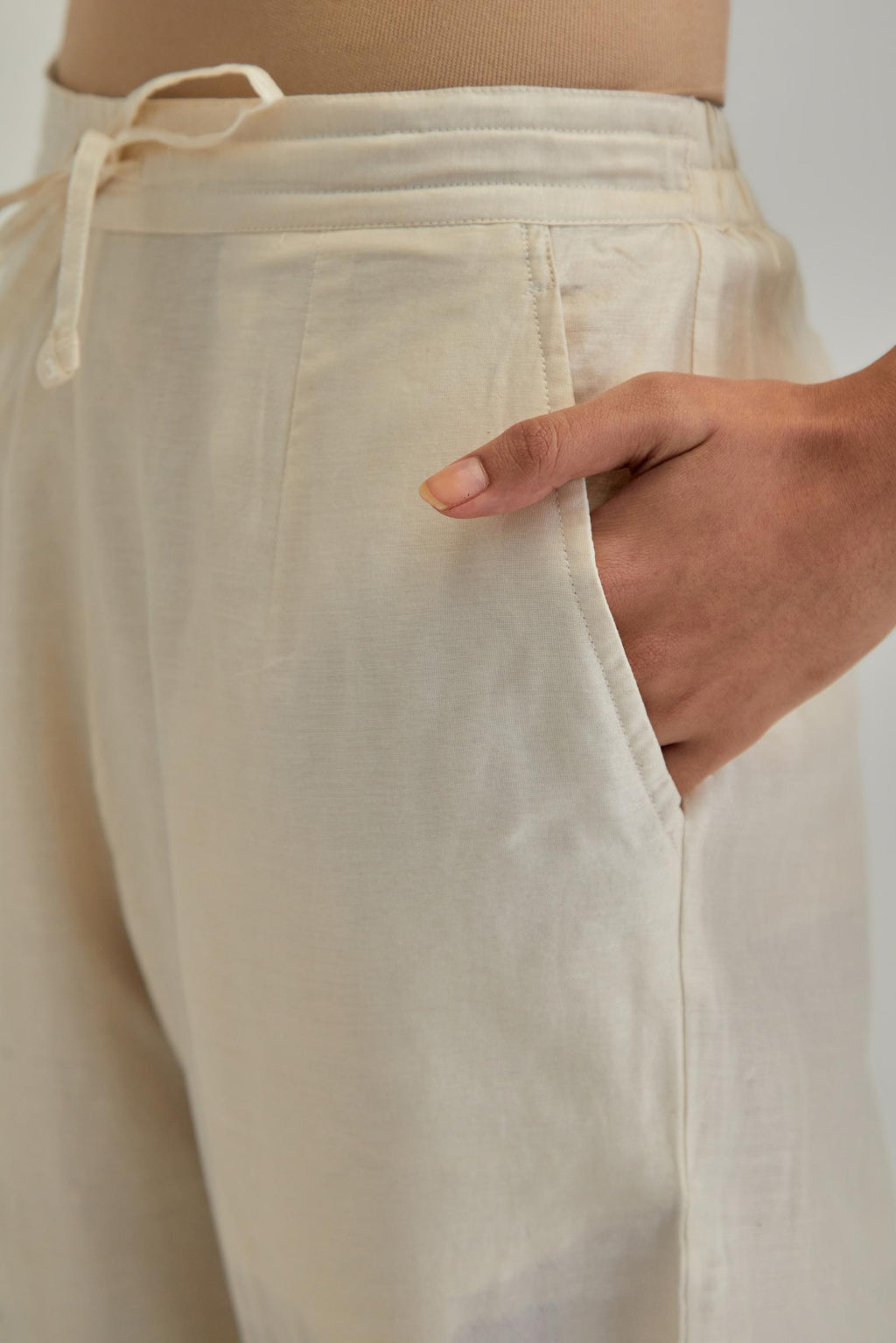 Off white silk Chanderi straight pants with earthy coloured appliqué at hem.