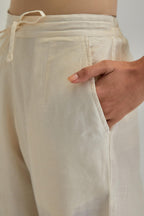Off white silk Chanderi straight pants with earthy coloured appliqué at hem.