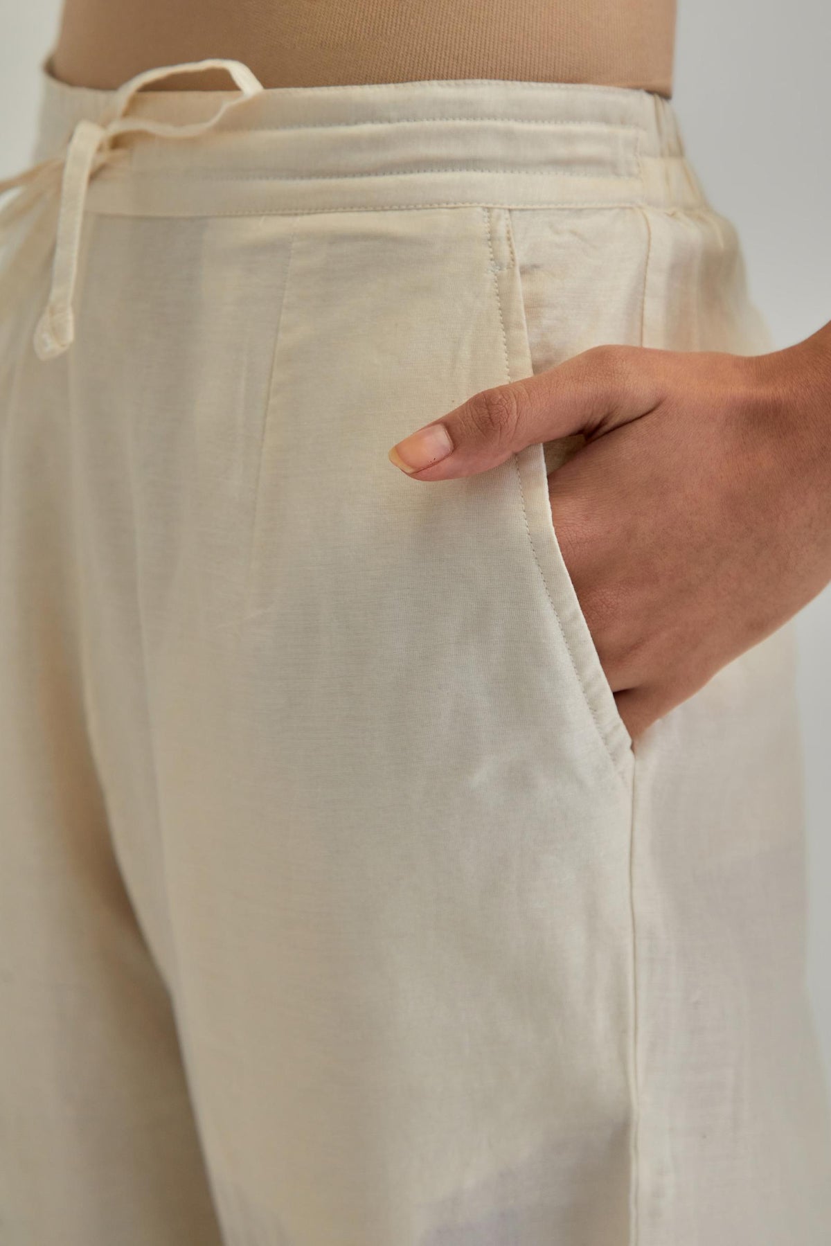 Off white silk Chanderi straight pants with earthy coloured appliqué at hem.
