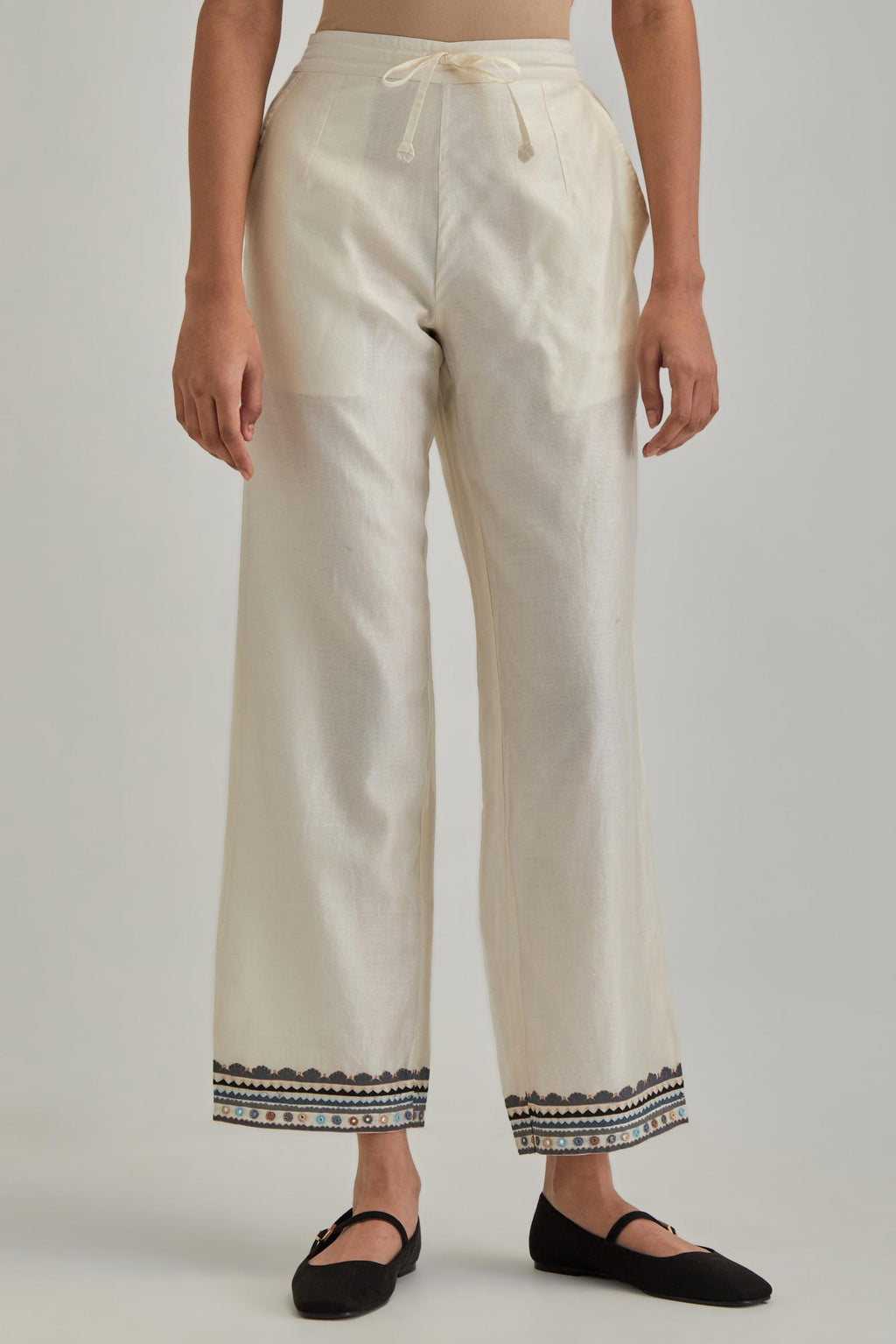 Off white silk Chanderi straight pants with earthy coloured applique and Aari thread work at hem.