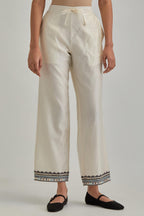 Off white silk Chanderi straight pants with earthy coloured applique and Aari thread work at hem.