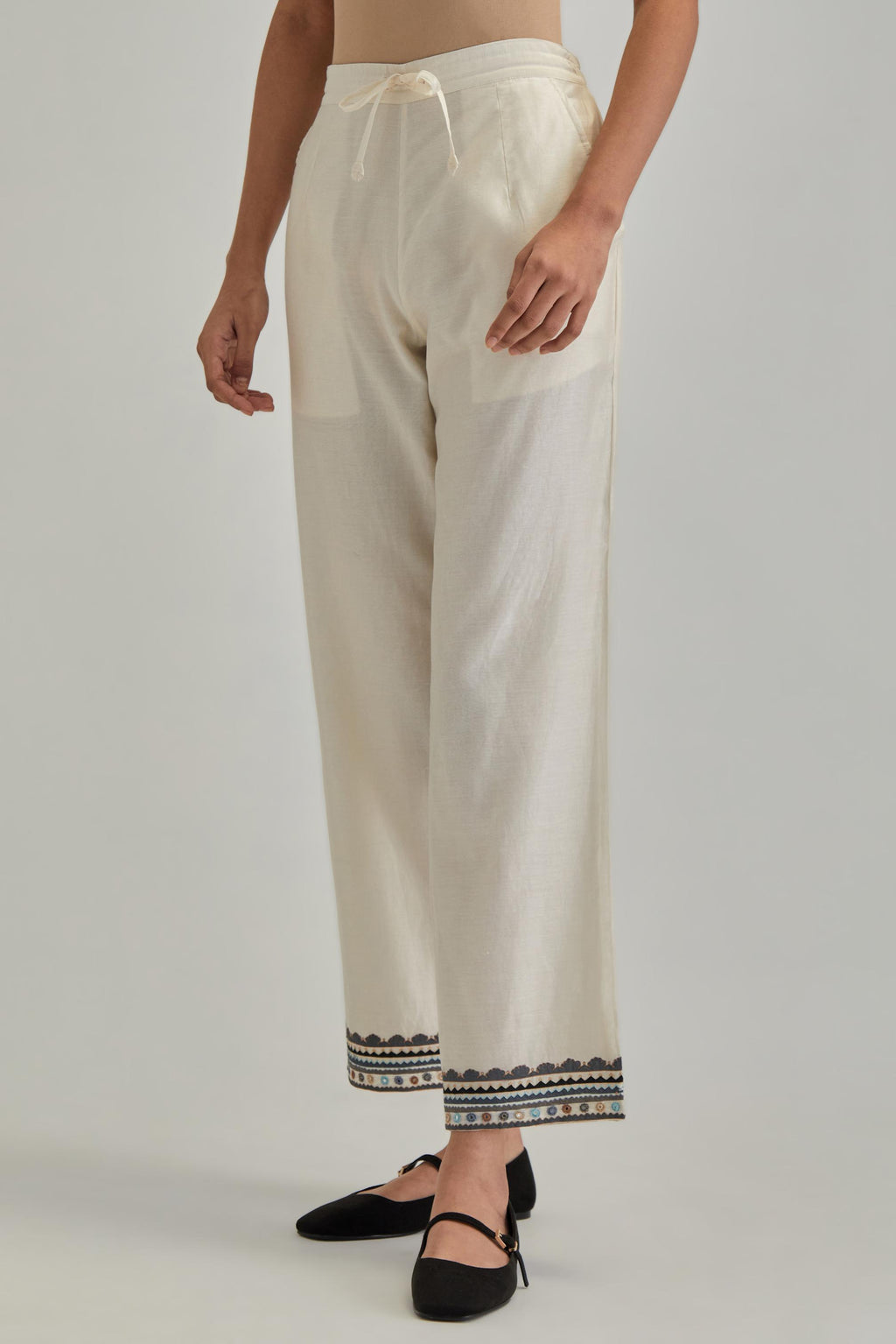 Off white silk Chanderi straight pants with earthy coloured applique and Aari thread work at hem.