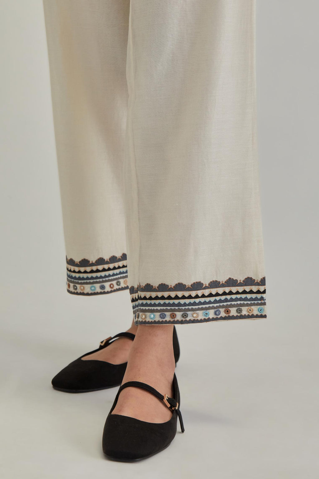 Off white silk Chanderi straight pants with earthy coloured applique and Aari thread work at hem.