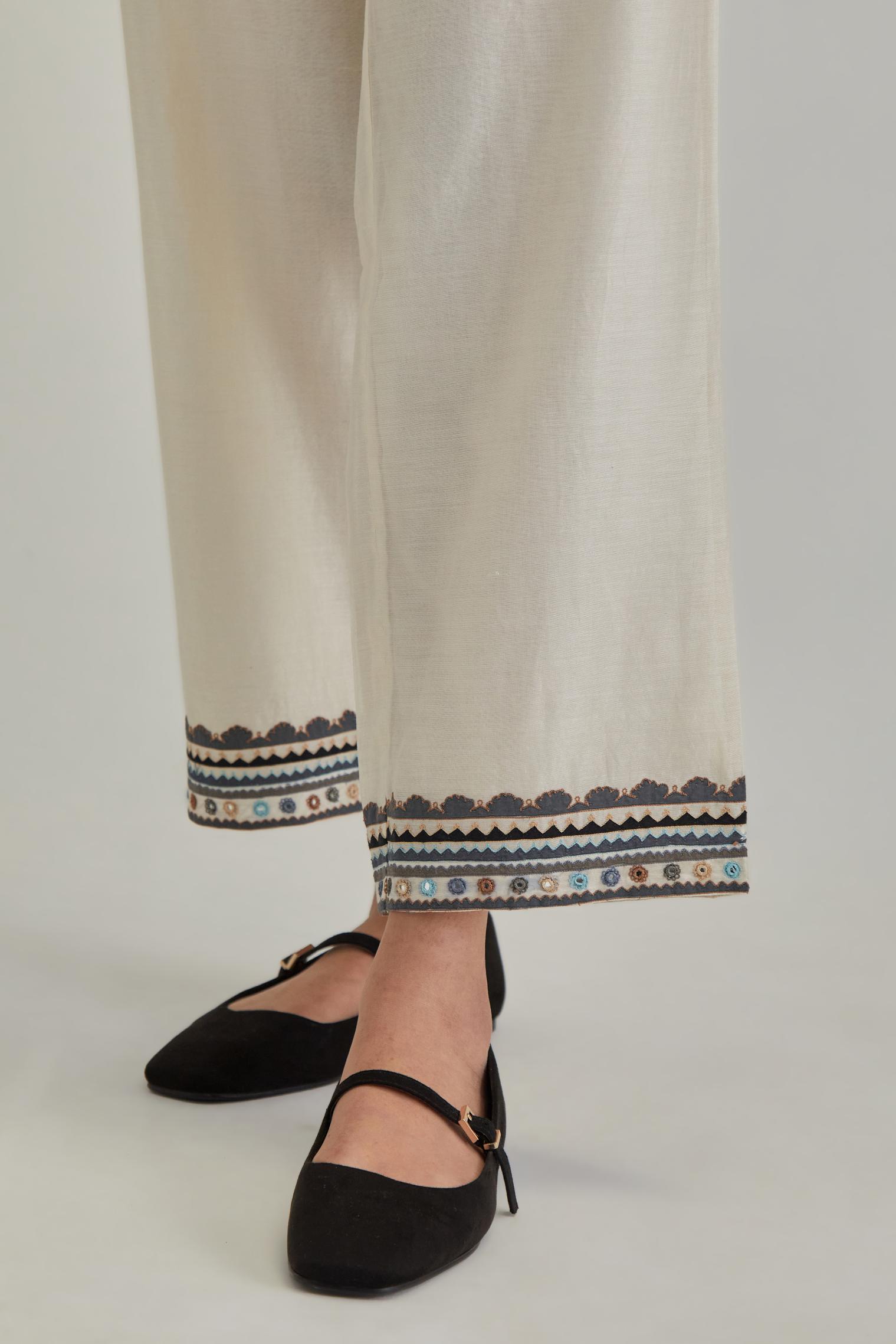 Off white silk Chanderi straight pants with earthy coloured applique and Aari thread work at hem.