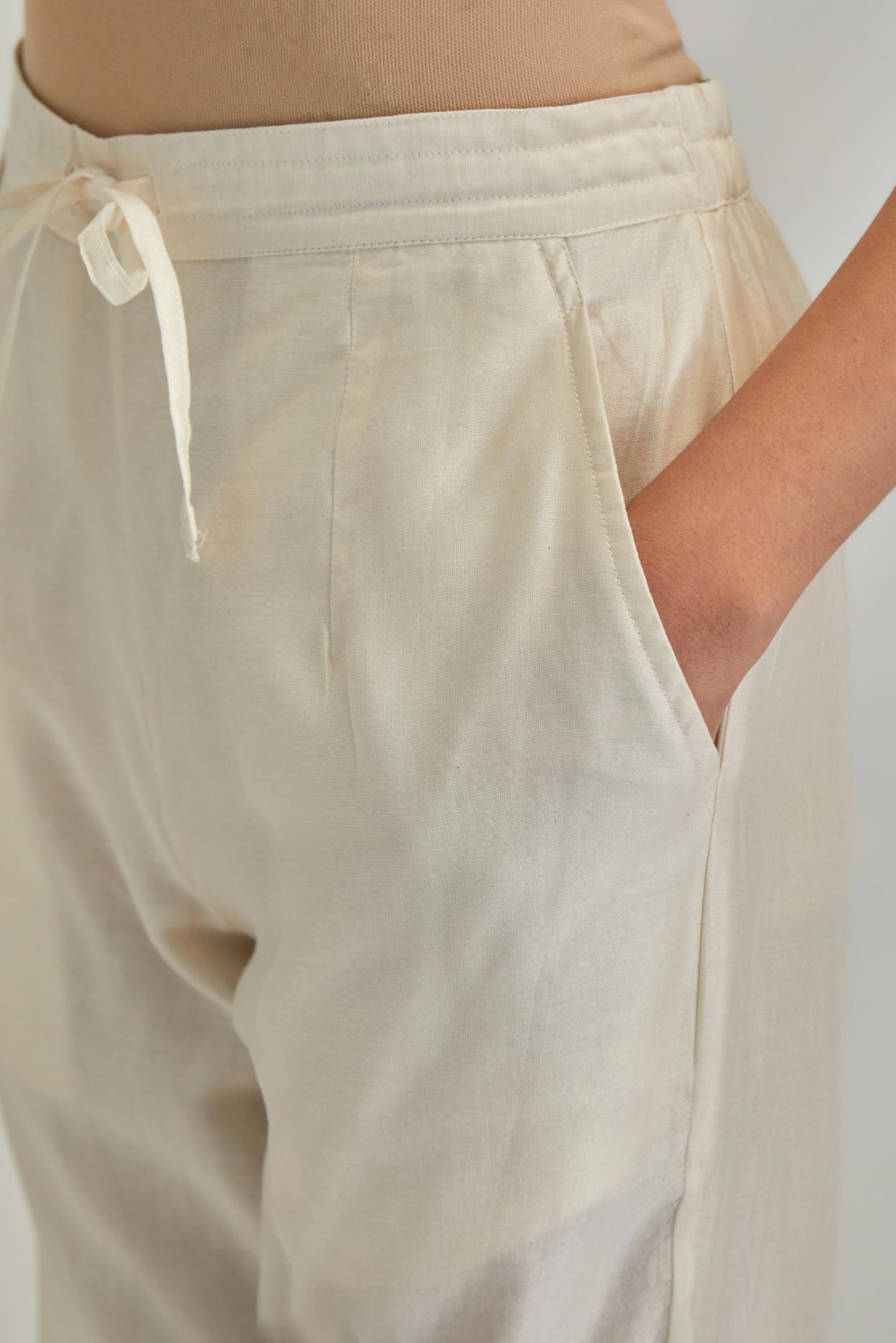 Off white silk Chanderi straight pants with earthy coloured applique and Aari thread work at hem.
