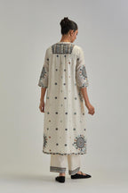 Off White silk Chanderi gathered kurta-dress set with appliqué stripes along with Aari thread work flowers and floral trellises along with a circular appliqued motif.