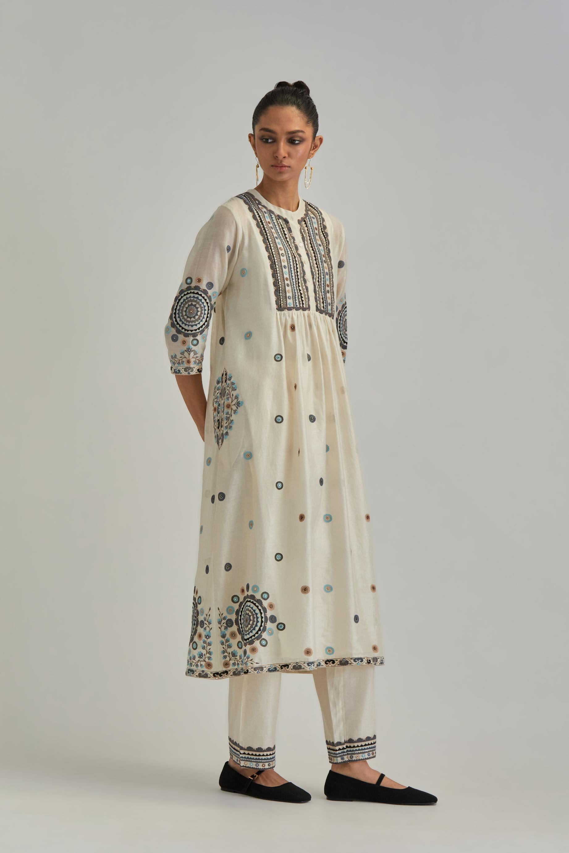 Off White silk Chanderi gathered kurta-dress set with appliqué stripes along with Aari thread work flowers and floral trellises along with a circular appliqued motif.