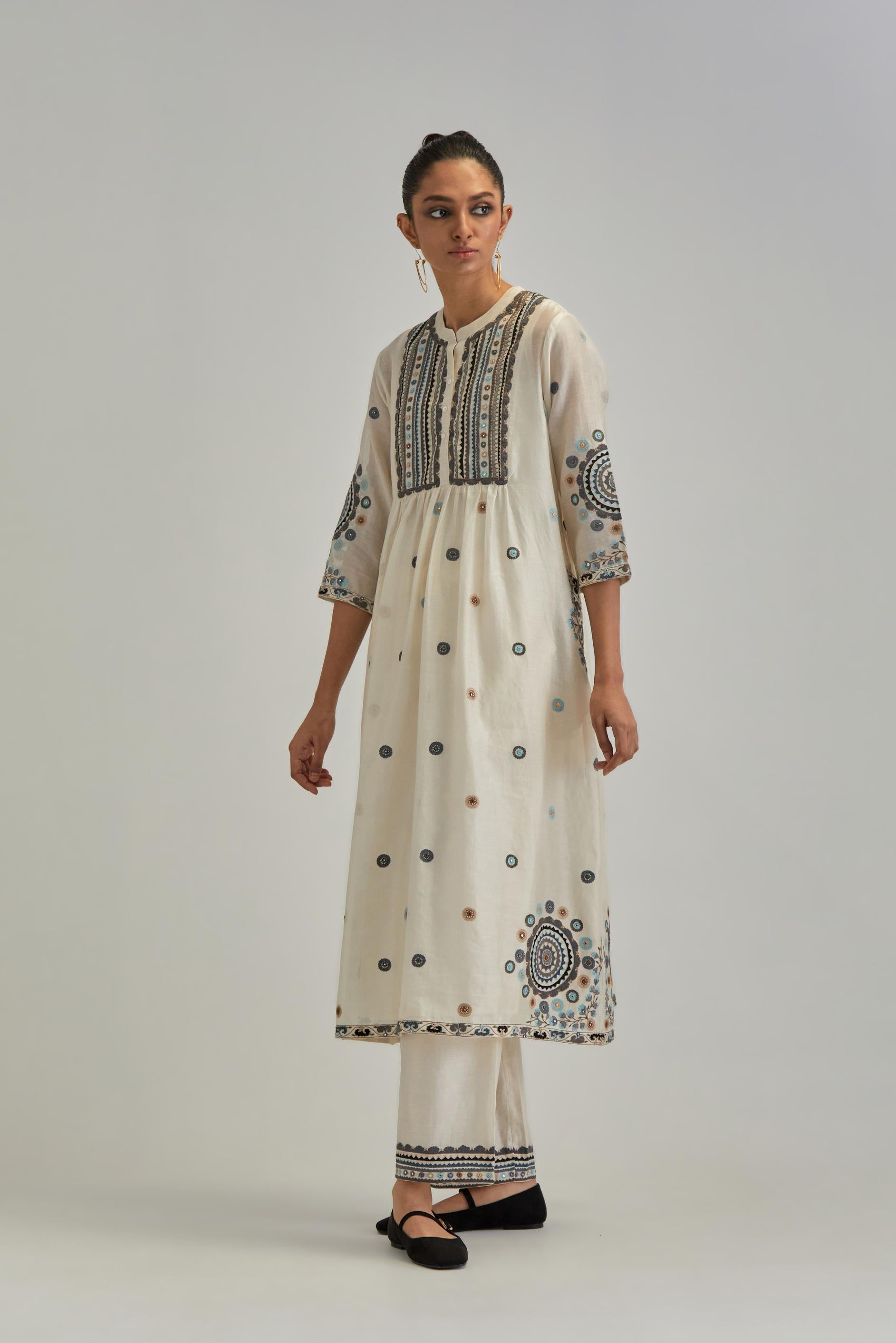 Off White silk Chanderi gathered kurta-dress set with appliqué stripes along with Aari thread work flowers and floral trellises along with a circular appliqued motif.