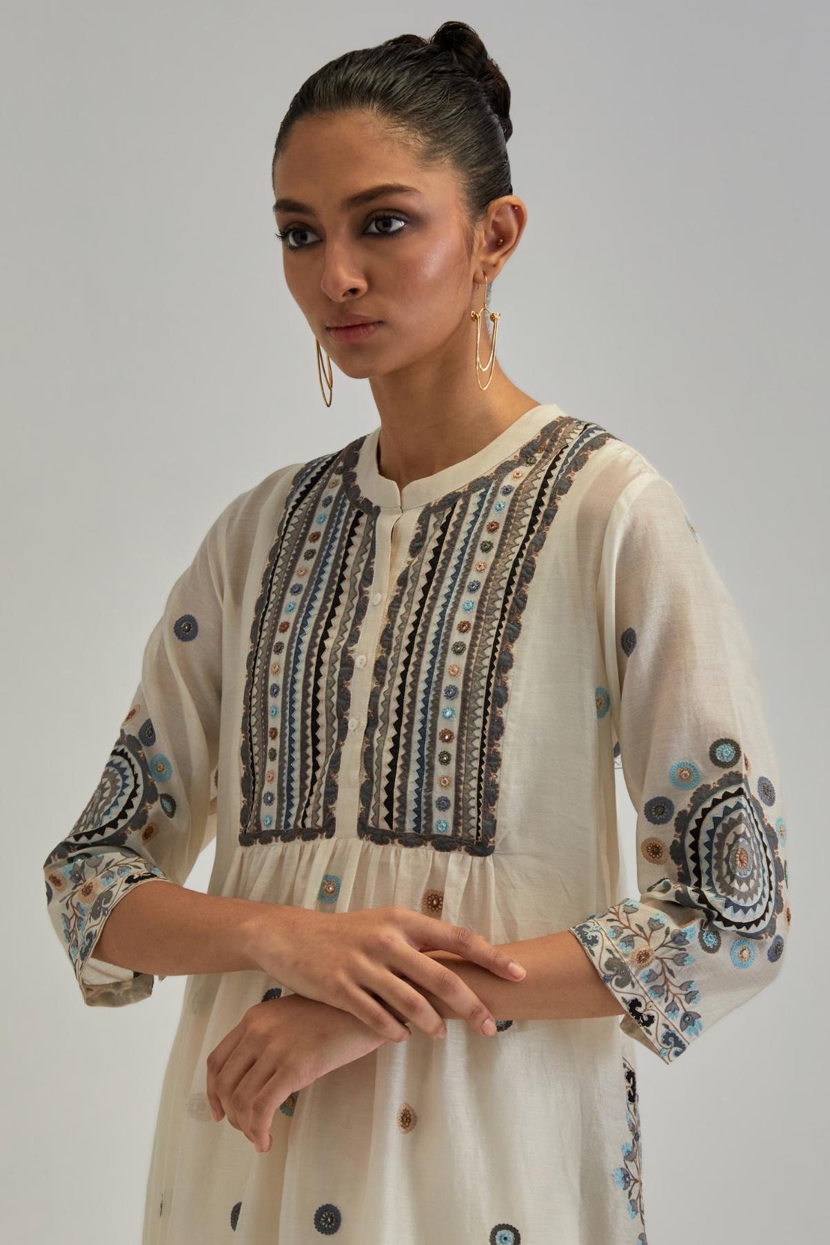 Off White silk Chanderi gathered kurta-dress set with appliqué stripes along with Aari thread work flowers and floral trellises along with a circular appliqued motif.