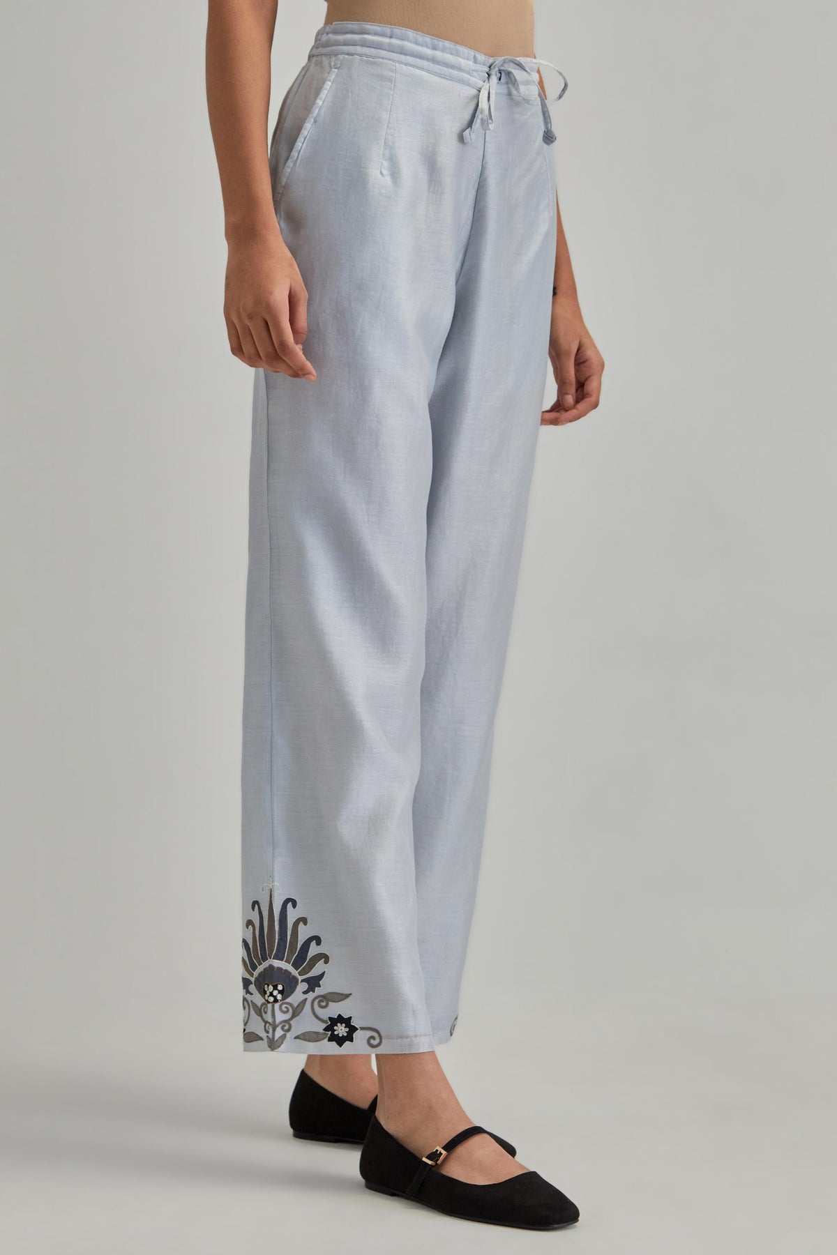 Blue silk Chanderi straight pants with earthy coloured appliqué at hem.