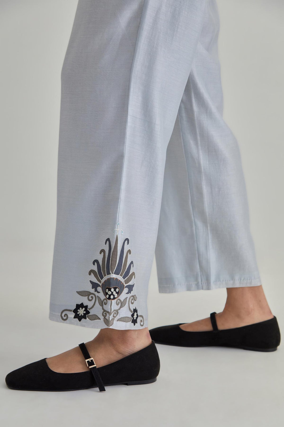 Blue silk Chanderi straight pants with earthy coloured appliqué at hem.