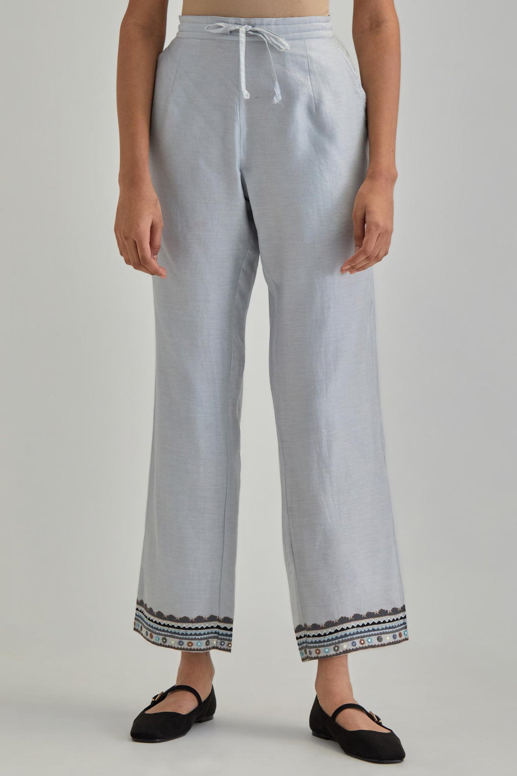 Blue silk Chanderi straight pants with earthy coloured applique and Aari thread work at hem.