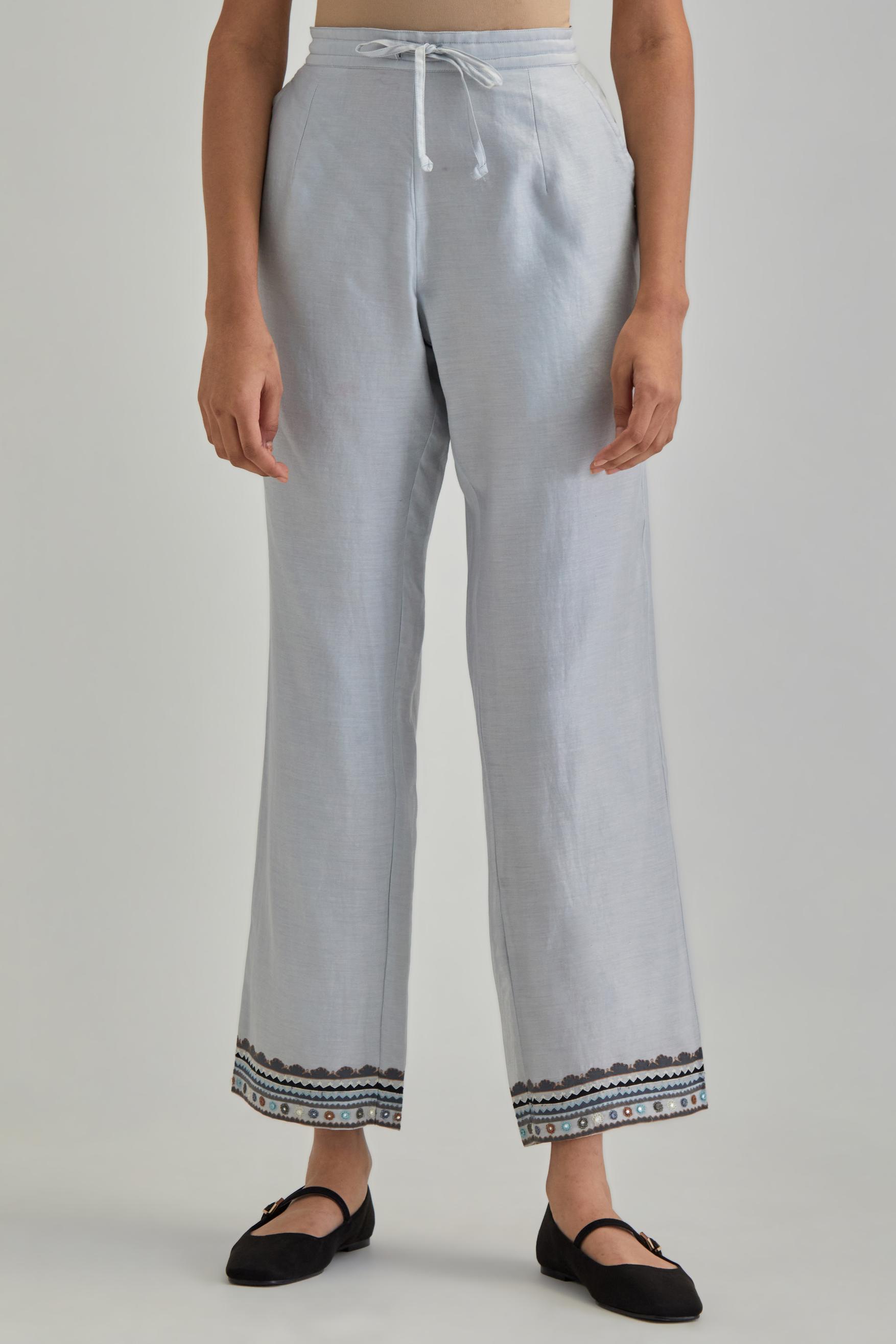 Blue silk Chanderi straight pants with earthy coloured applique and Aari thread work at hem.