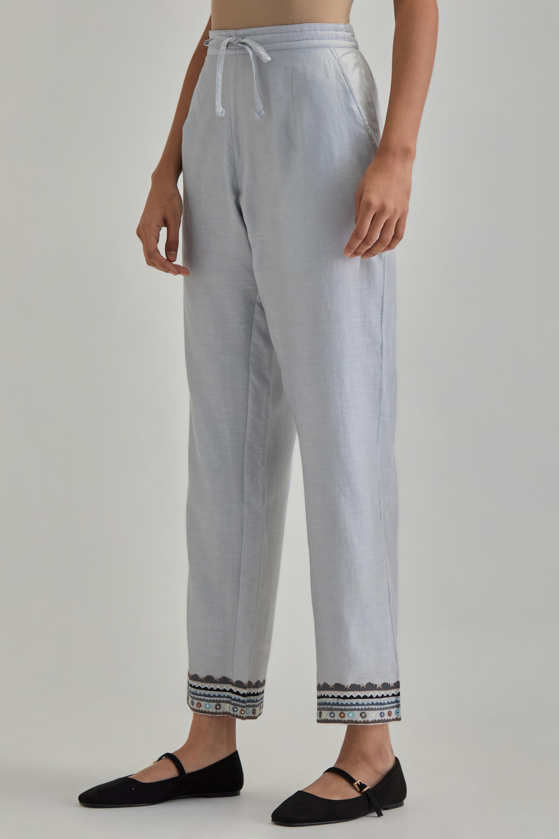 Blue silk Chanderi straight pants with earthy coloured applique and Aari thread work at hem.