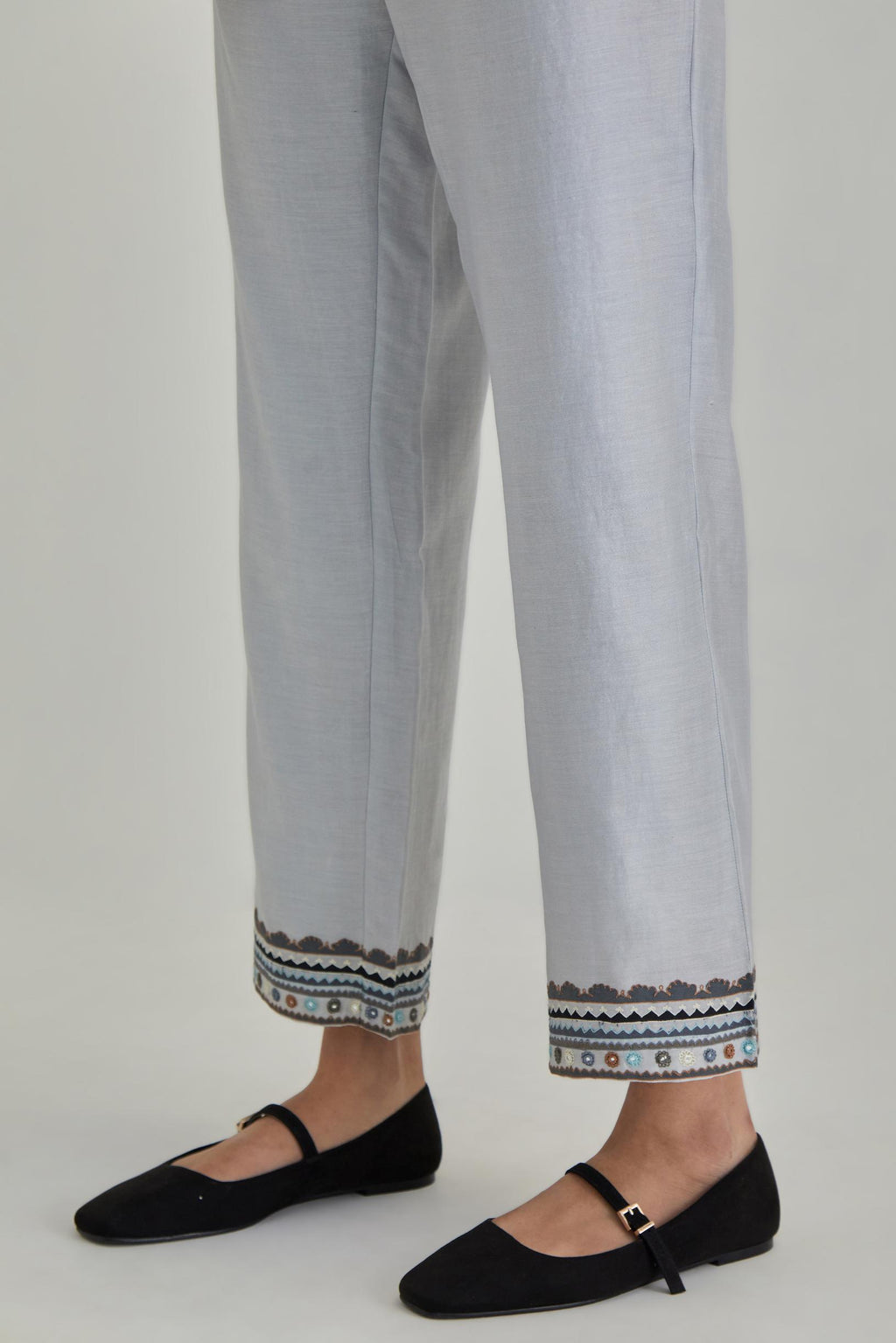 Blue silk Chanderi straight pants with earthy coloured applique and Aari thread work at hem.