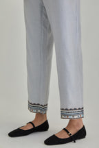 Blue silk Chanderi straight pants with earthy coloured applique and Aari thread work at hem.