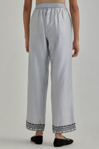 Blue silk Chanderi straight pants with earthy coloured applique and Aari thread work at hem.