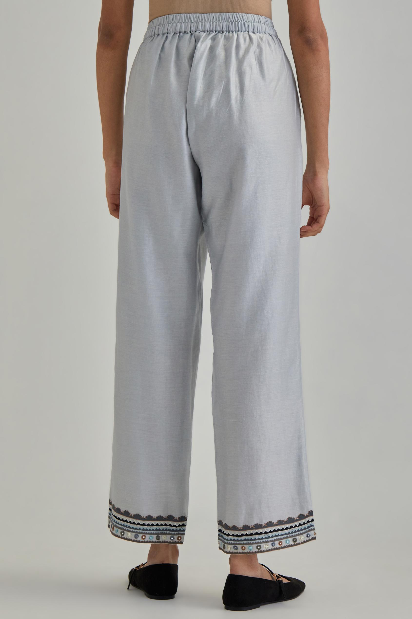 Blue silk Chanderi straight pants with earthy coloured applique and Aari thread work at hem.