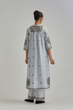 Blue silk Chanderi gathered kurta-dress set with appliqué stripes along with aari thread work flowers and floral trellises along with a circular appliqued motif.