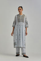 Blue silk Chanderi gathered kurta-dress set with appliqué stripes along with aari thread work flowers and floral trellises along with a circular appliqued motif.