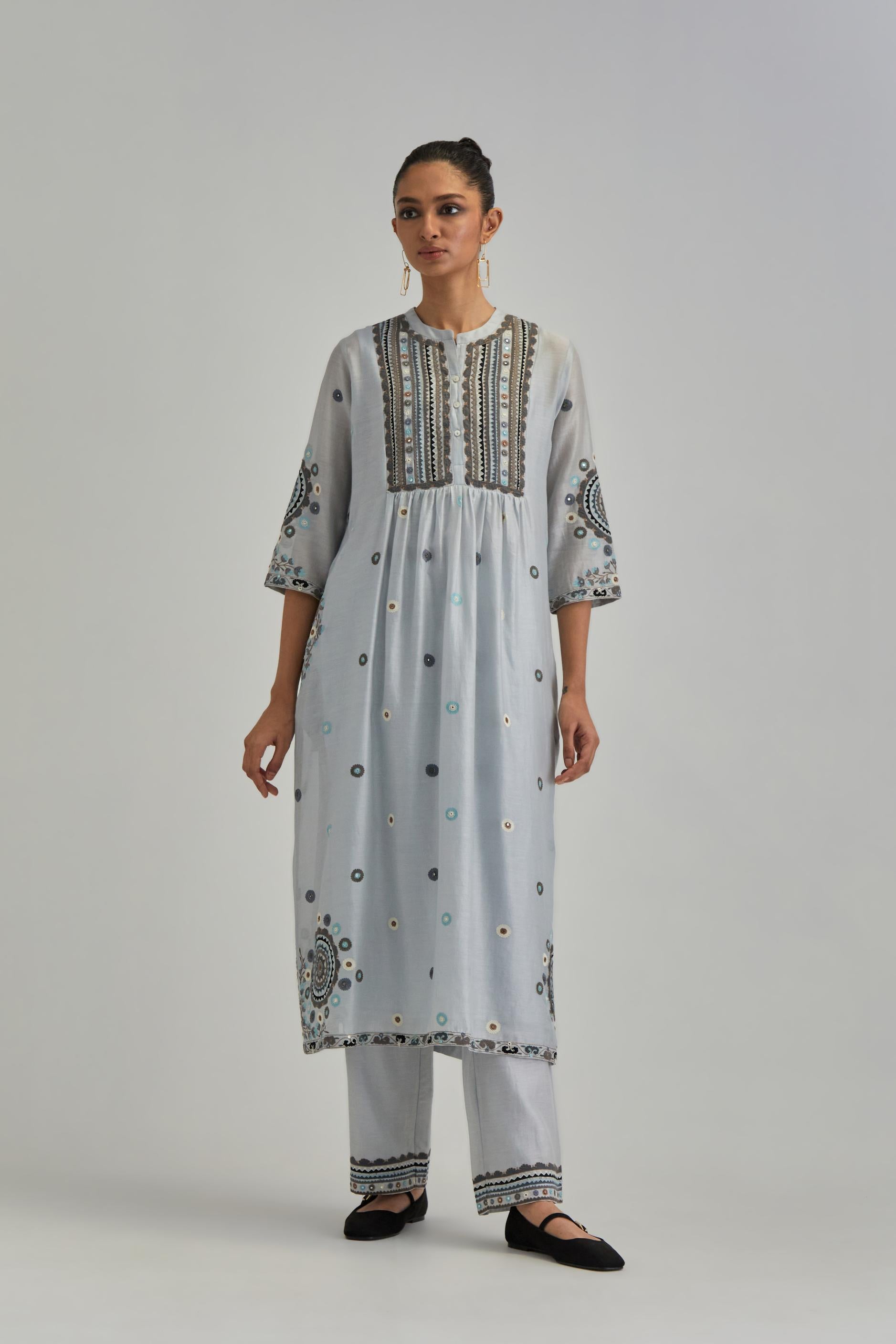 Blue silk Chanderi gathered kurta-dress set with appliqué stripes along with aari thread work flowers and floral trellises along with a circular appliqued motif.