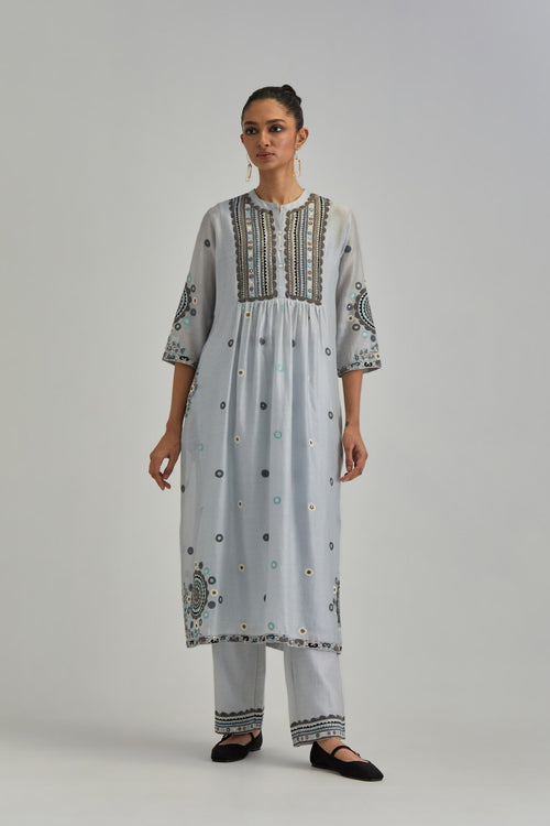 Blue silk Chanderi gathered kurta-dress set with appliqué stripes along with aari thread work flowers and floral trellises along with a circular appliqued motif.