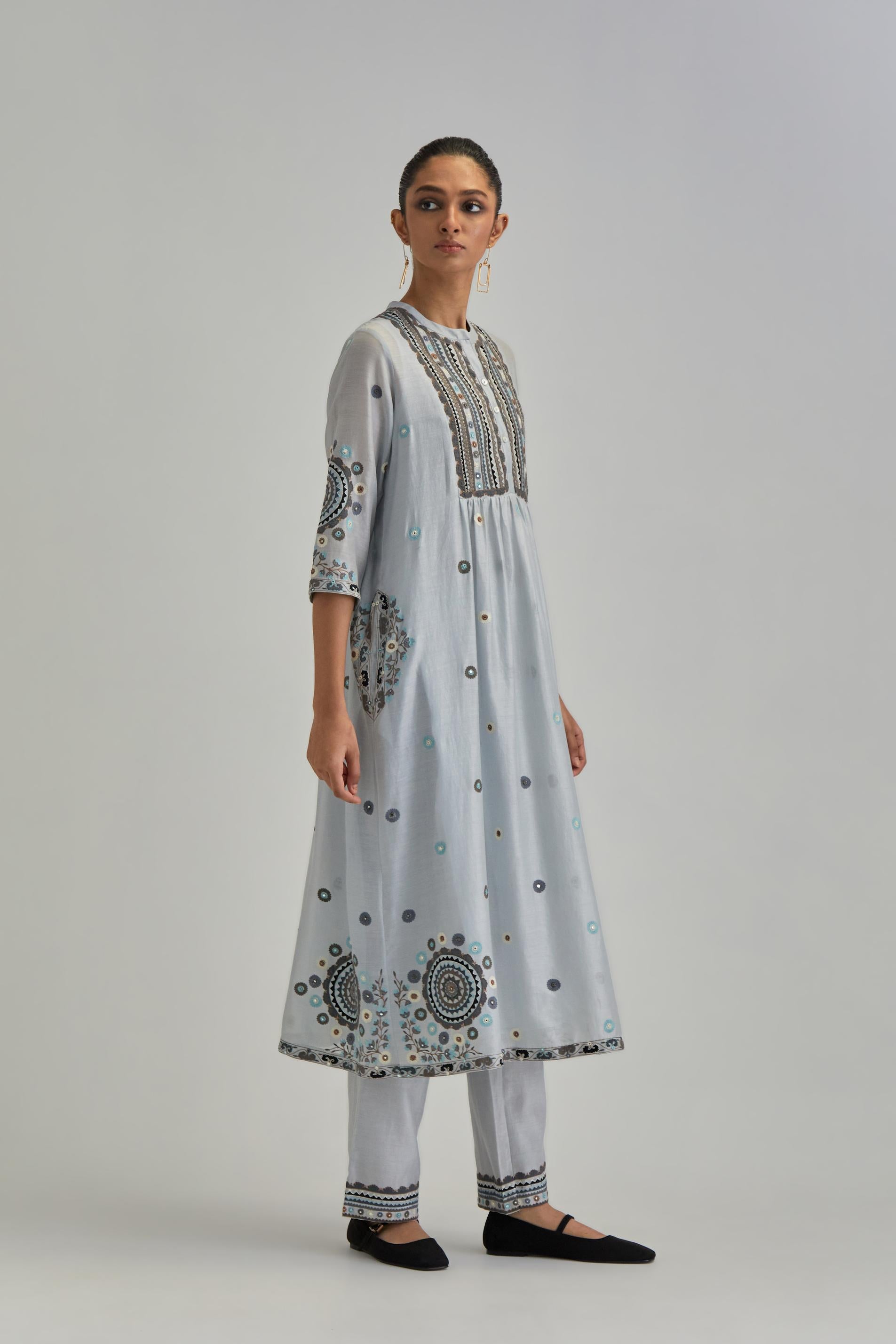 Blue silk Chanderi gathered kurta-dress set with appliqué stripes along with aari thread work flowers and floral trellises along with a circular appliqued motif.