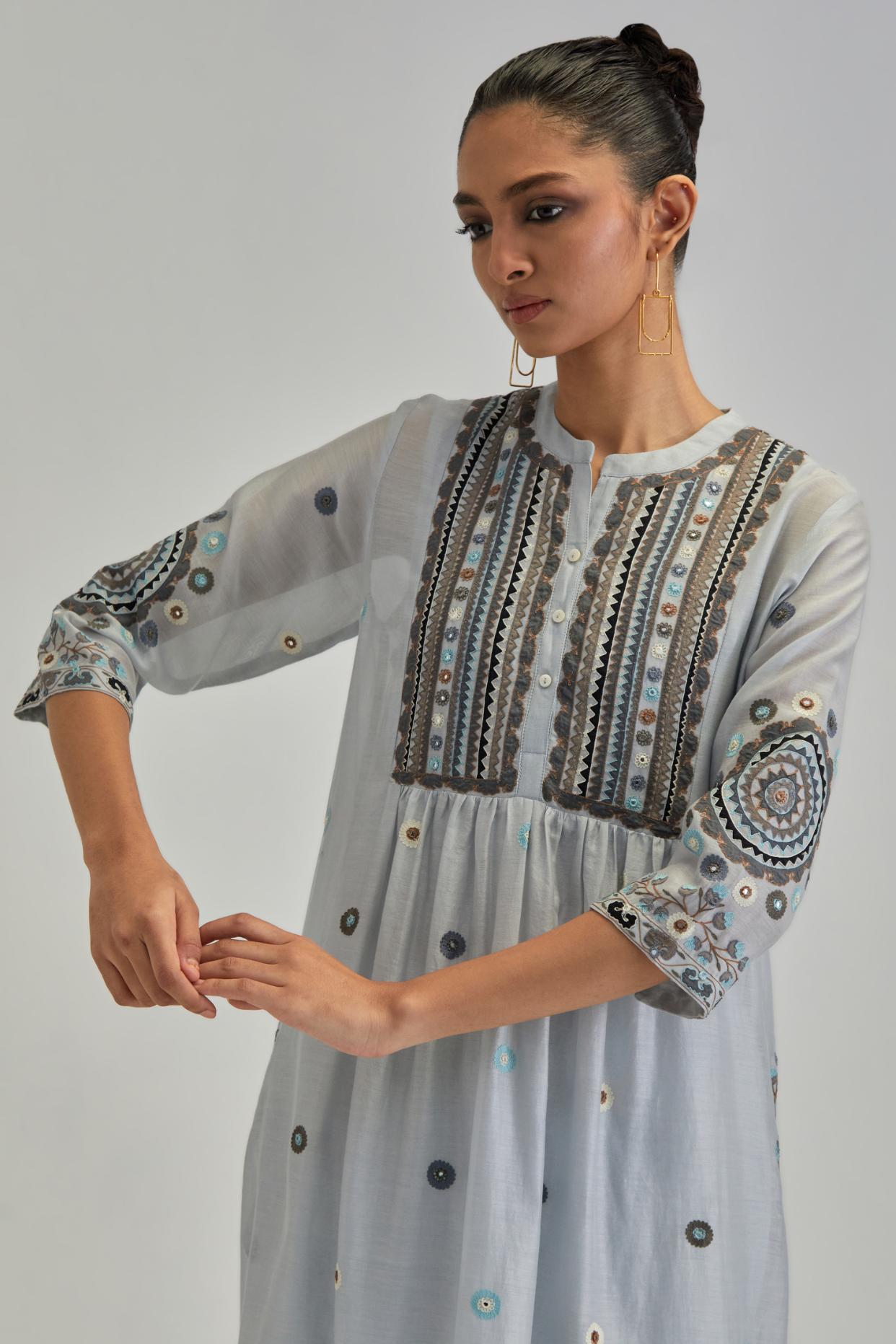 Blue silk Chanderi gathered kurta-dress set with appliqué stripes along with aari thread work flowers and floral trellises along with a circular appliqued motif.