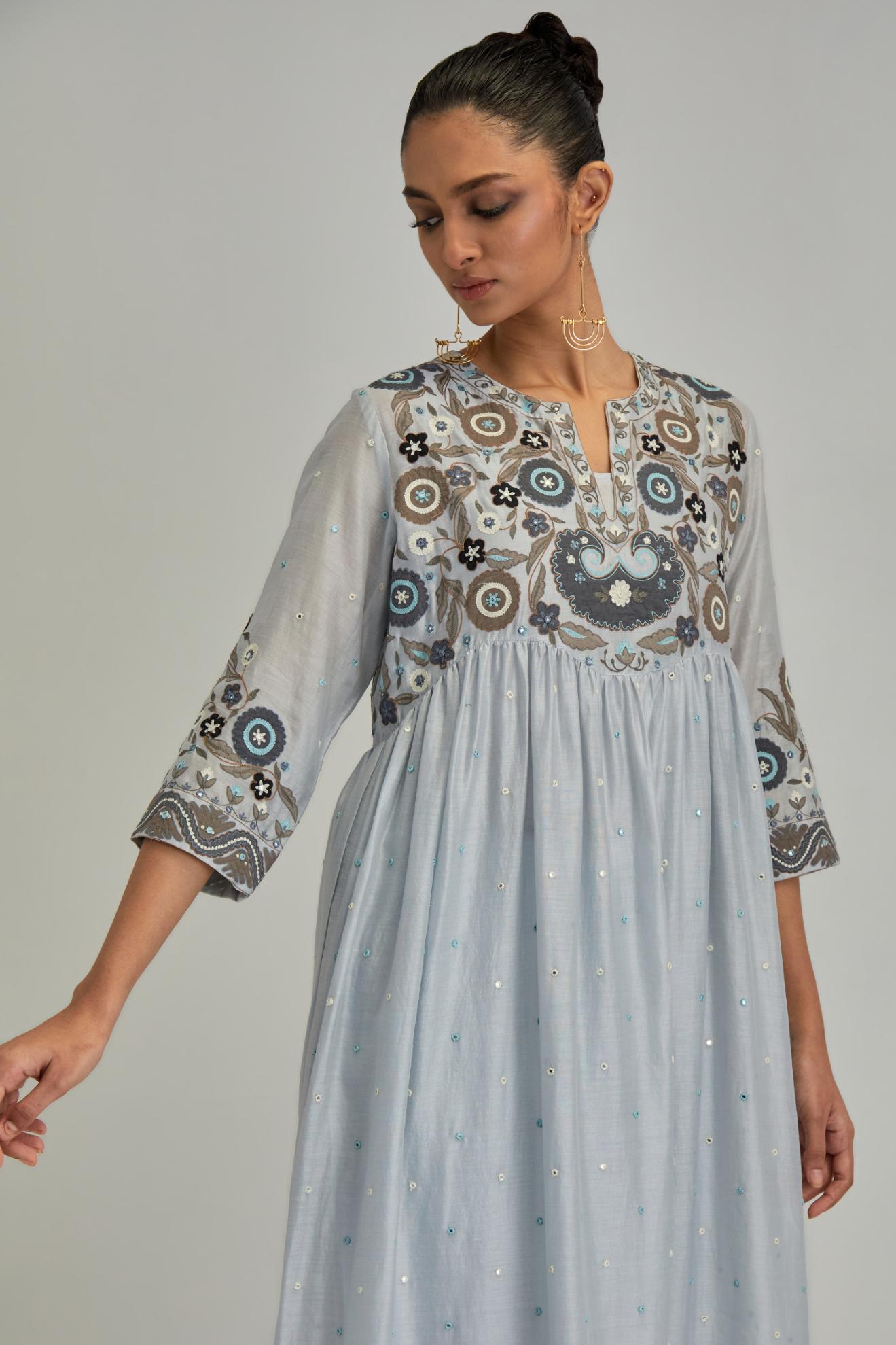 Blue silk Chanderi kurta-dress set with a wavy high-waist and fine gathers. The yoke is fully embroidered with earthy coloured circular appliqué and Aari thread work.