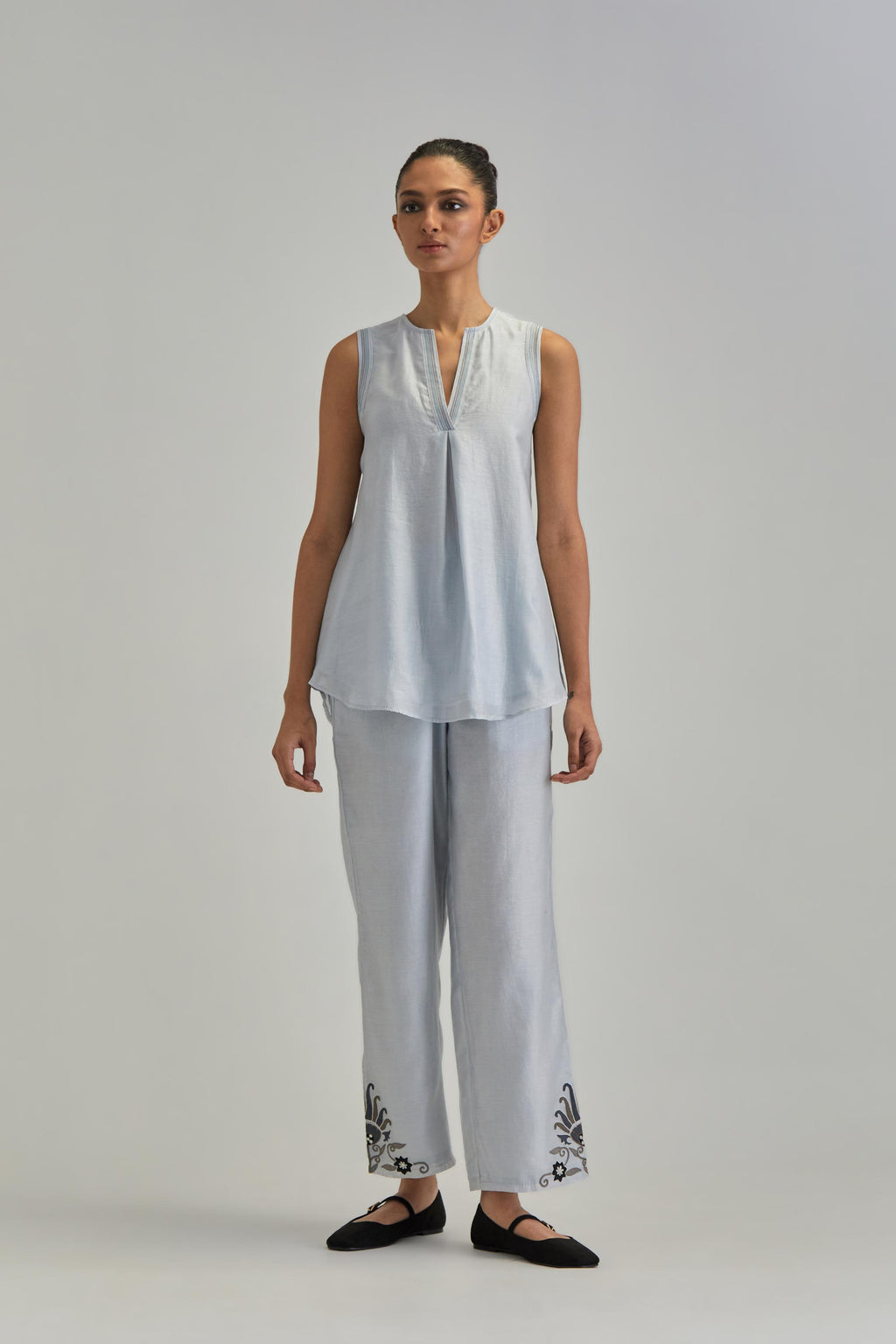 Blue short front open A-line jacket, fully embroidered with bold appliqué flowers, earthy-coloured Aari thread work and silk tassels, paired with Blue silk Chanderi straight pants with earthy coloured appliqué at hem.