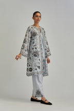 Blue short front open A-line jacket, fully embroidered with bold appliqué flowers, earthy-coloured Aari thread work and silk tassels, paired with Blue silk Chanderi straight pants with earthy coloured appliqué at hem.