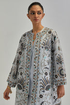 Blue short front open A-line jacket, fully embroidered with bold appliqué flowers, earthy-coloured Aari thread work and silk tassels, paired with Blue silk Chanderi straight pants with earthy coloured appliqué at hem.