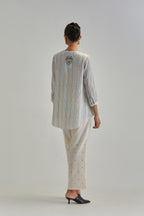 Off White short top with thin multi-coloured stripe hand block print and earthy coloured Aari thread embroidery, paired with Off White silk Chanderi straight pants with mirror work, highlighted with earthy coloured thread work.