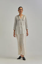 Off White short top with thin multi-coloured stripe hand block print and earthy coloured Aari thread embroidery, paired with Off White silk Chanderi straight pants with mirror work, highlighted with earthy coloured thread work.