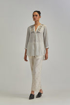 Off White short top with thin multi-coloured stripe hand block print and earthy coloured Aari thread embroidery, paired with Off White silk Chanderi straight pants with mirror work, highlighted with earthy coloured thread work.