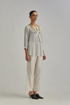 Off White short top with thin multi-coloured stripe hand block print and earthy coloured Aari thread embroidery, paired with Off White silk Chanderi straight pants with mirror work, highlighted with earthy coloured thread work.