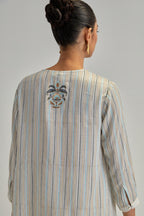 Off White short top with thin multi-coloured stripe hand block print and earthy coloured Aari thread embroidery, paired with Off White silk Chanderi straight pants with mirror work, highlighted with earthy coloured thread work.