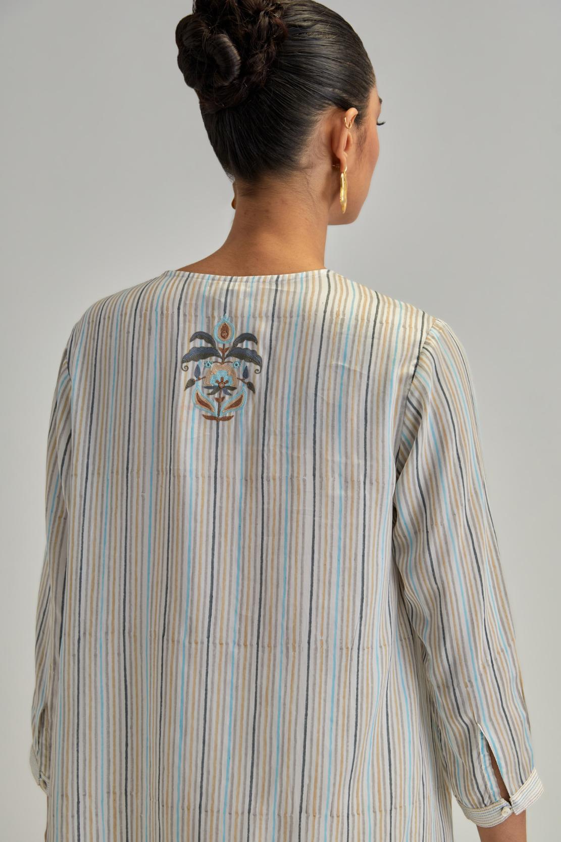 Off White short top with thin multi-coloured stripe hand block print and earthy coloured Aari thread embroidery, paired with Off White silk Chanderi straight pants with mirror work, highlighted with earthy coloured thread work.