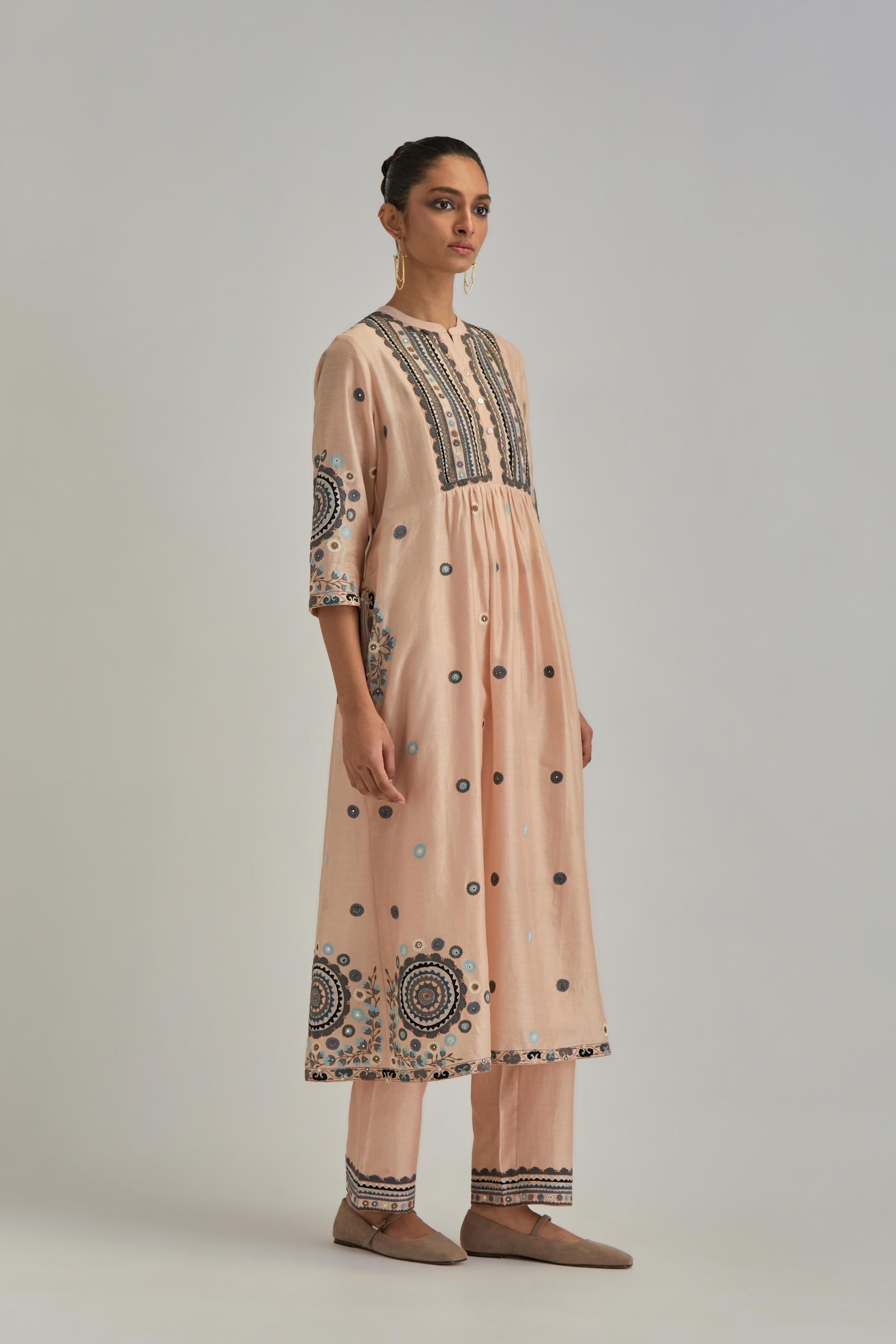 Pink silk Chanderi gathered kurta-dress set with appliqué stripes along with aari thread work flowers and floral trellises along with a circular appliqued motif.