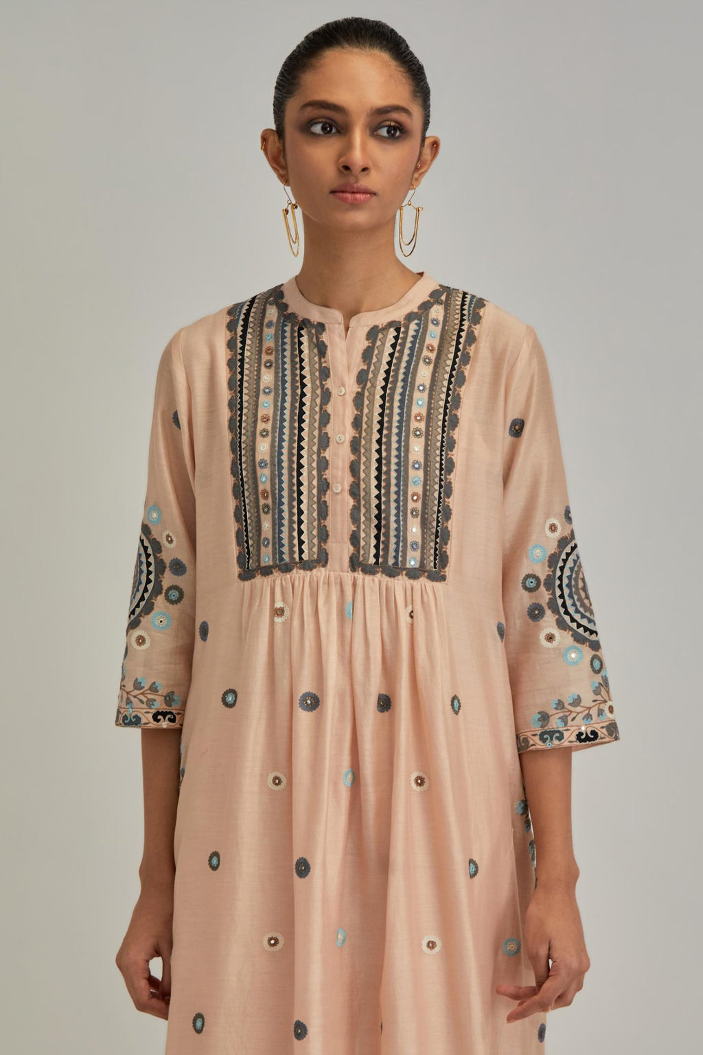 Pink silk Chanderi gathered kurta-dress set with appliqué stripes along with aari thread work flowers and floral trellises along with a circular appliqued motif.