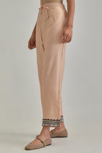 Pink silk Chanderi straight pants with earthy coloured applique and Aari thread work at hem.