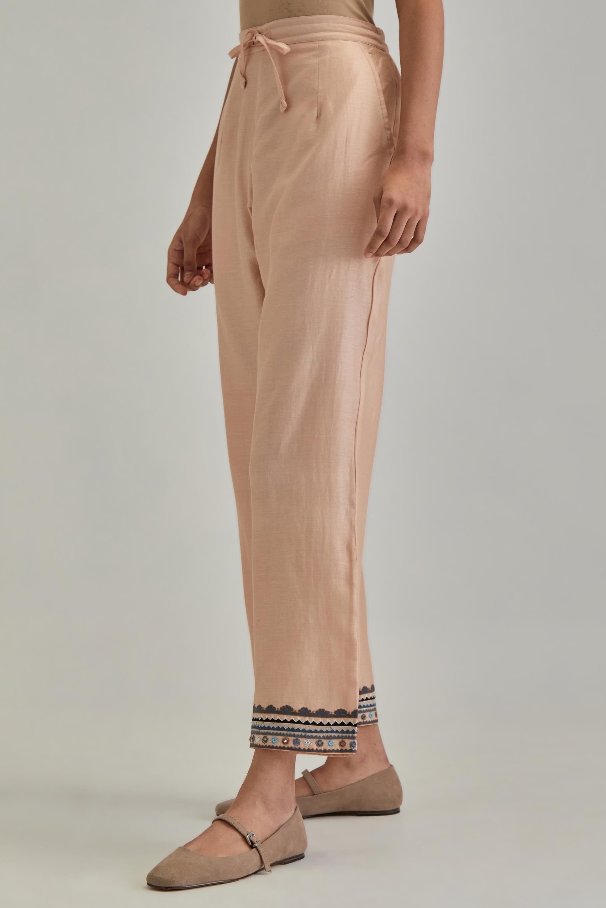 Pink silk Chanderi straight pants with earthy coloured applique and Aari thread work at hem.