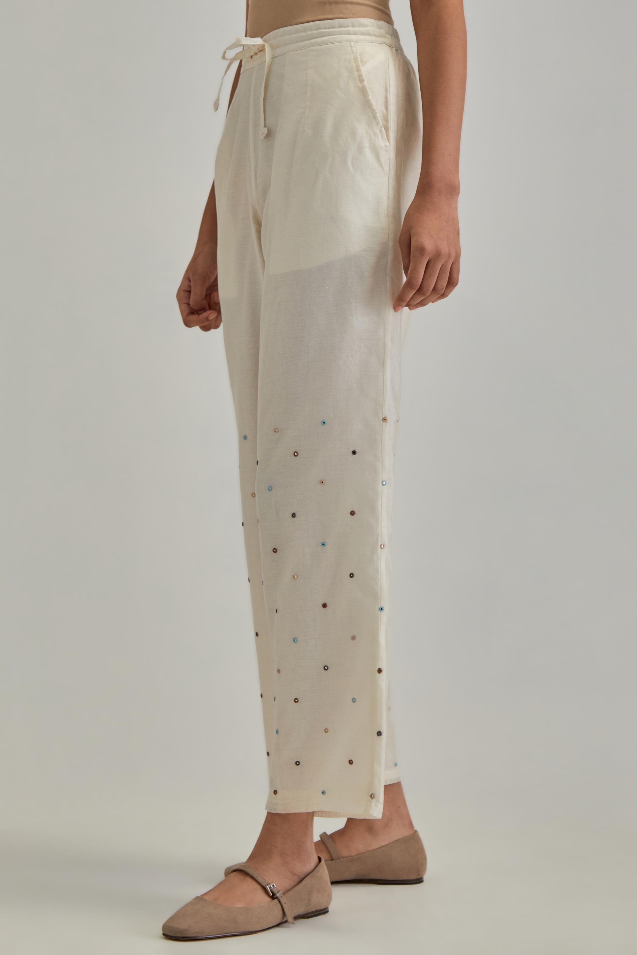 Off White silk Chanderi straight pants with mirror work, highlighted with earthy coloured thread work.
