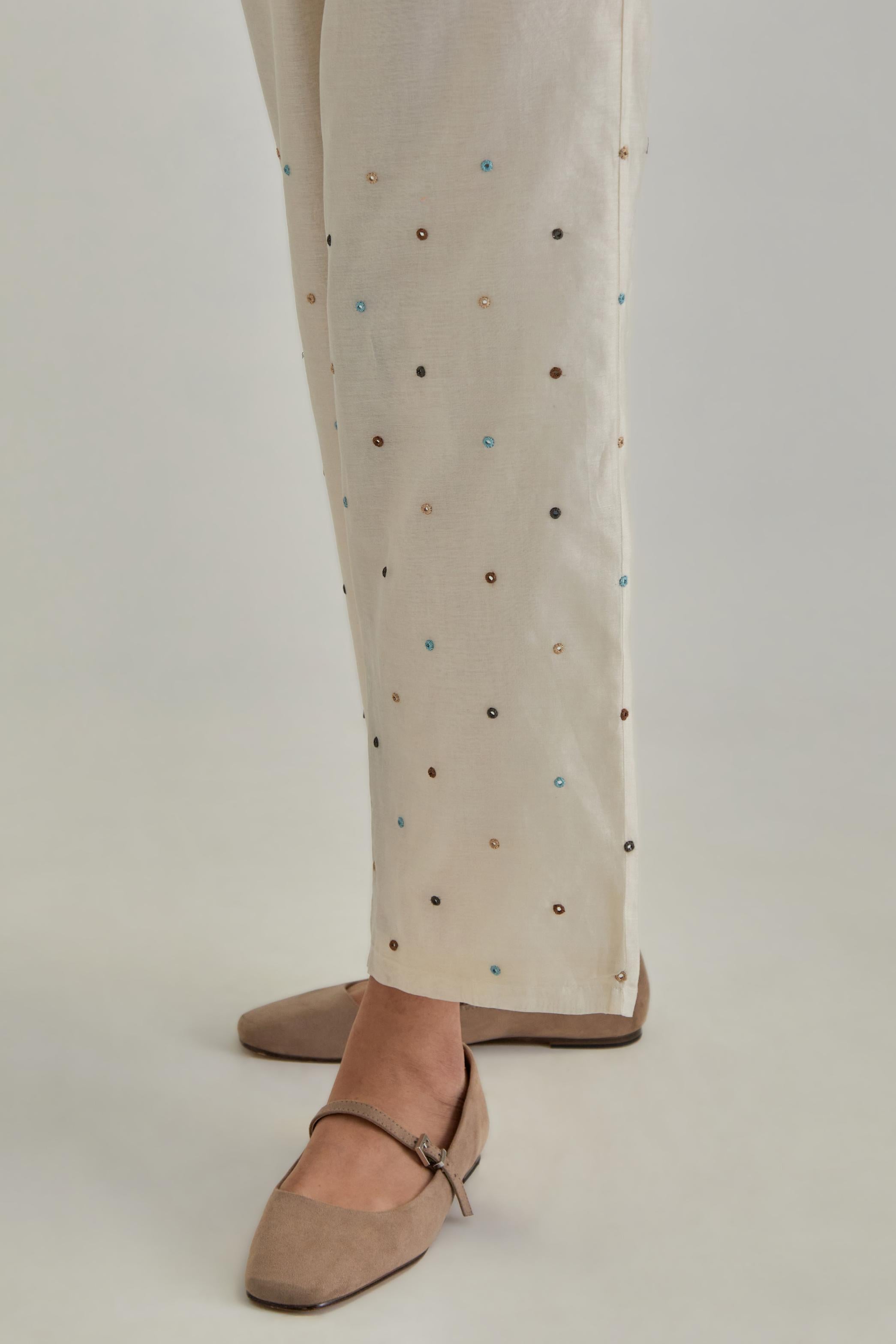 Off White silk Chanderi straight pants with mirror work, highlighted with earthy coloured thread work.