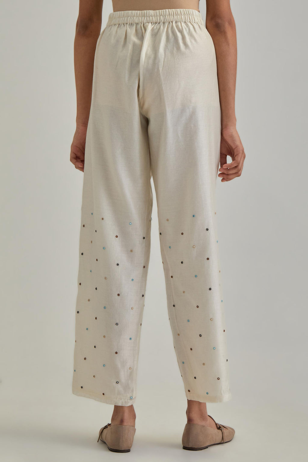 Off White silk Chanderi straight pants with mirror work, highlighted with earthy coloured thread work.