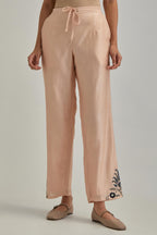 Pink silk Chanderi straight pants with earthy coloured appliqué at hem.
