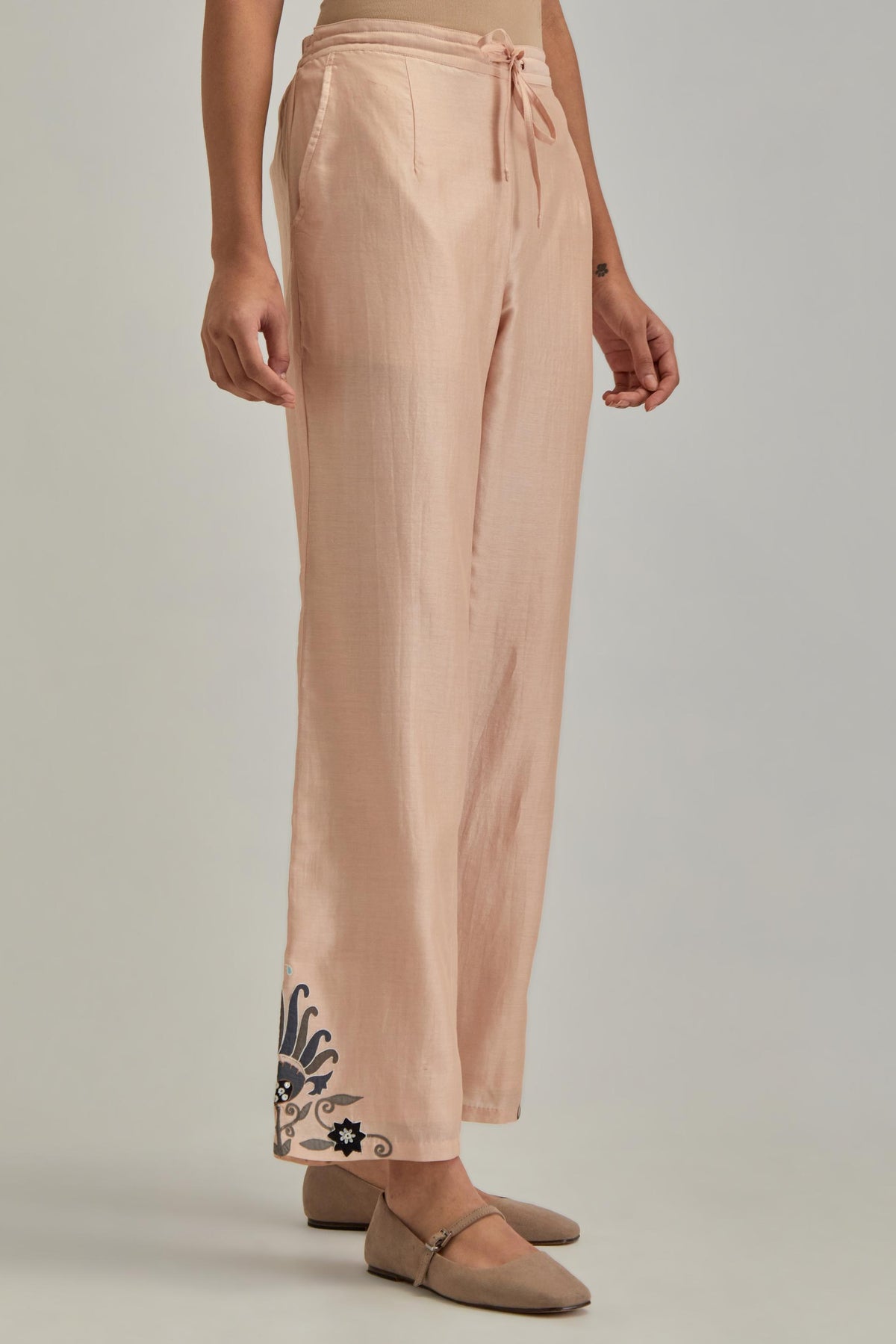 Pink silk Chanderi straight pants with earthy coloured appliqué at hem.