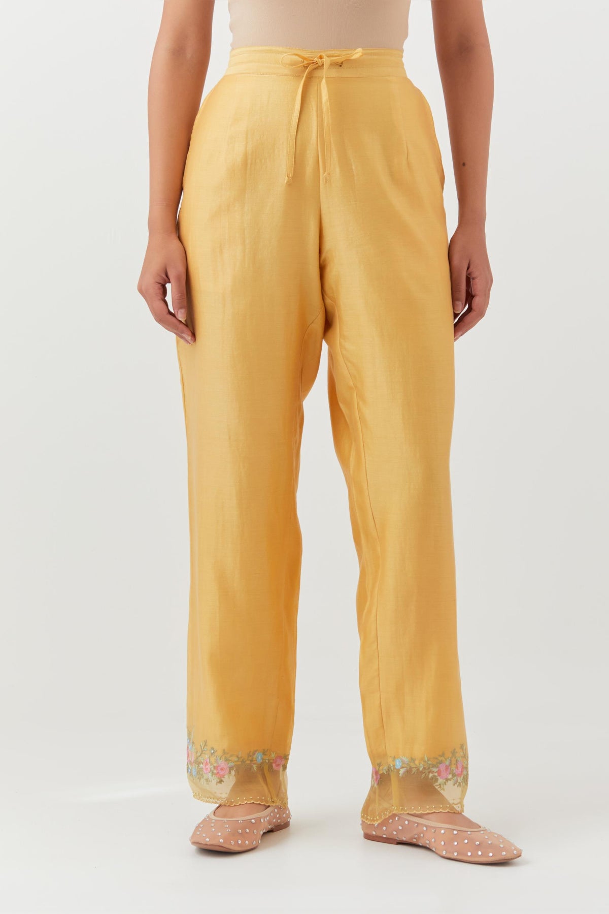 Yellow silk chanderi straight pants with a broad organza scalloped hem, highlighted with embroidered rose flower bunches and beads.