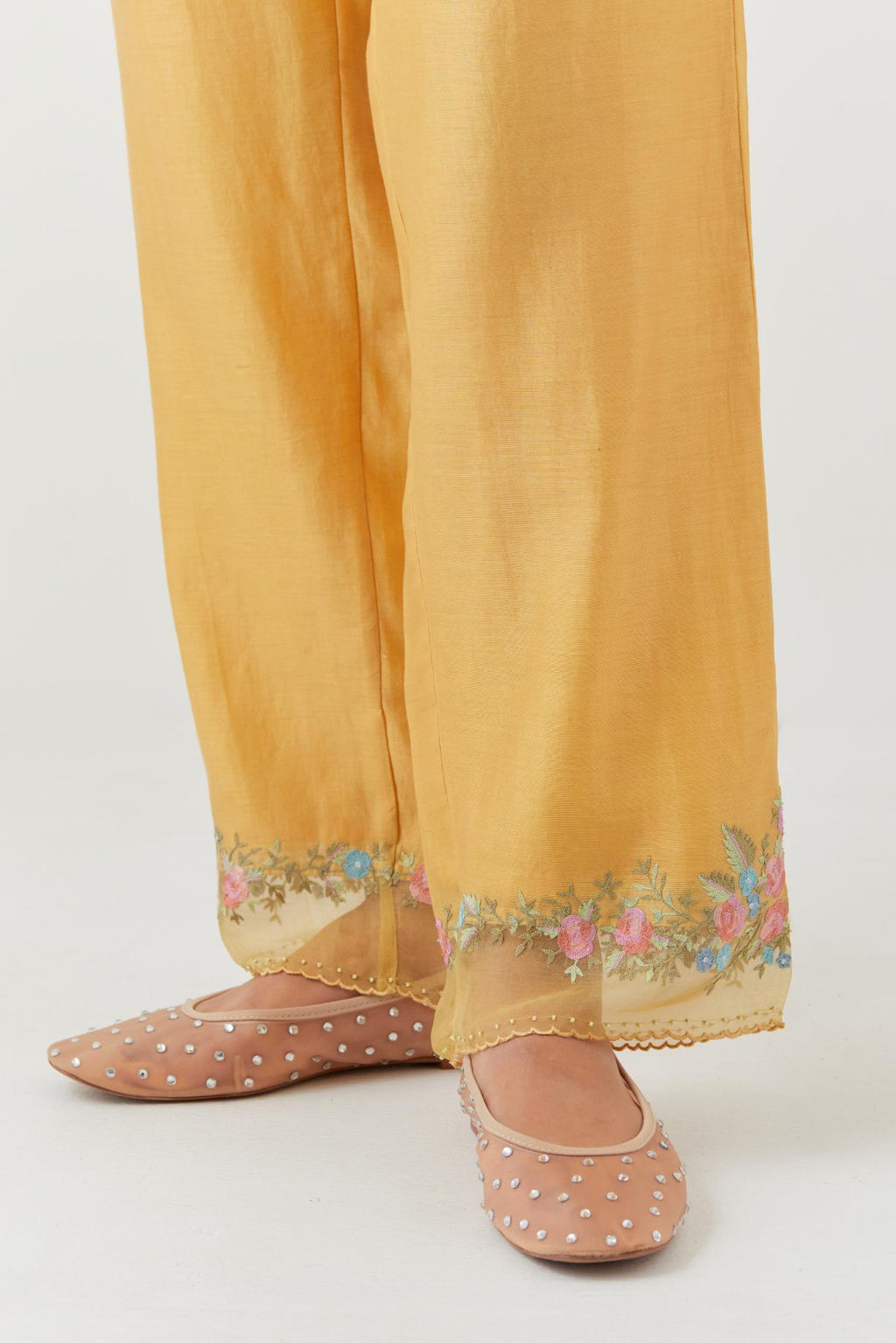 Yellow silk chanderi straight pants with a broad organza scalloped hem, highlighted with embroidered rose flower bunches and beads.